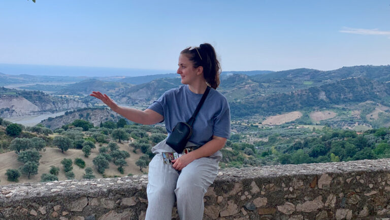 woman on wall in stilo italy; southern italy; solo travel female; how to solo travel; safety tips for women who travel; italian cooking class