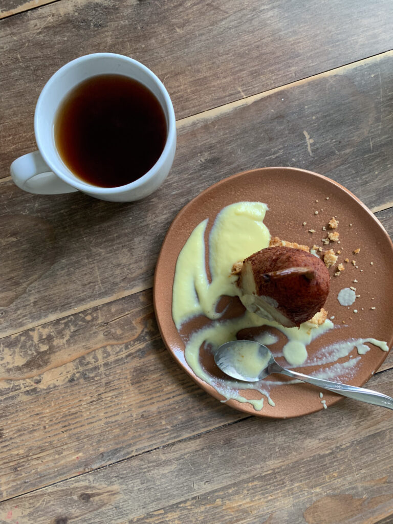 glaze in a pot with woman waving at her reflection for single serve spiced poached pear with streusel and creme anglaise