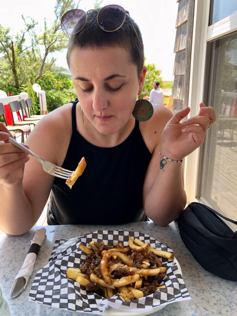 woman eating poutine in canada; light house on prince edward island in canada; mother daughter trip; canada road trip; red cliffs on prince edward island