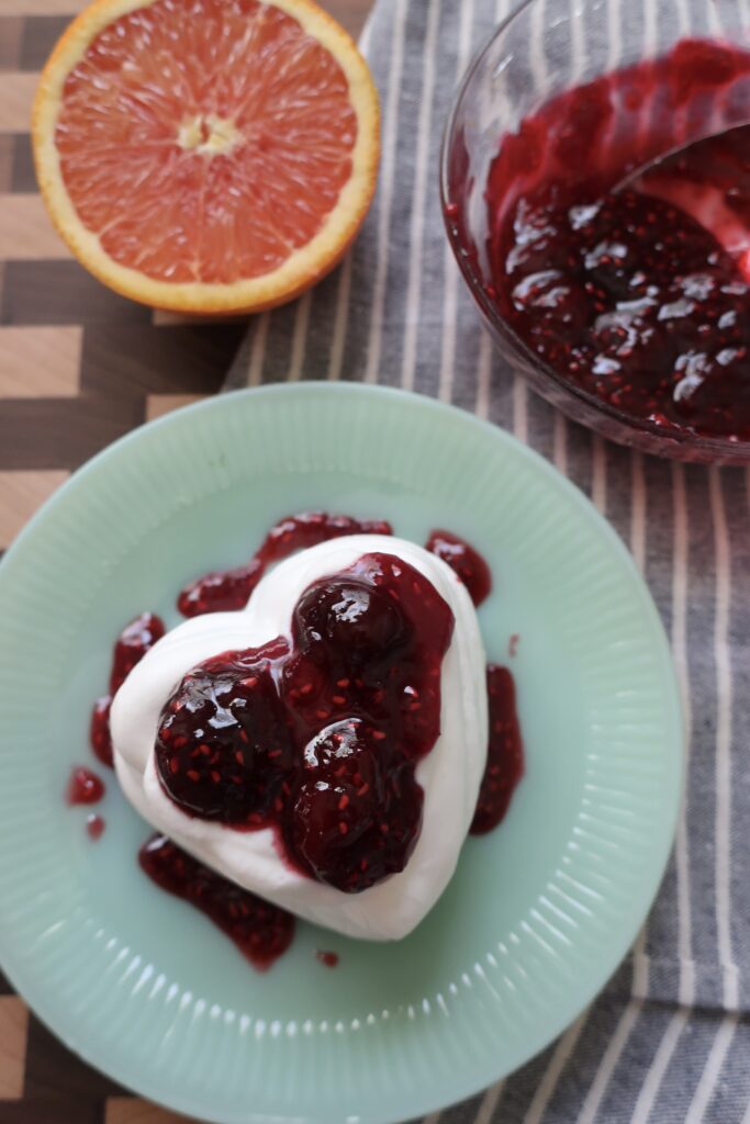 bowl of cherry berry compote on blue napkin with half of orange