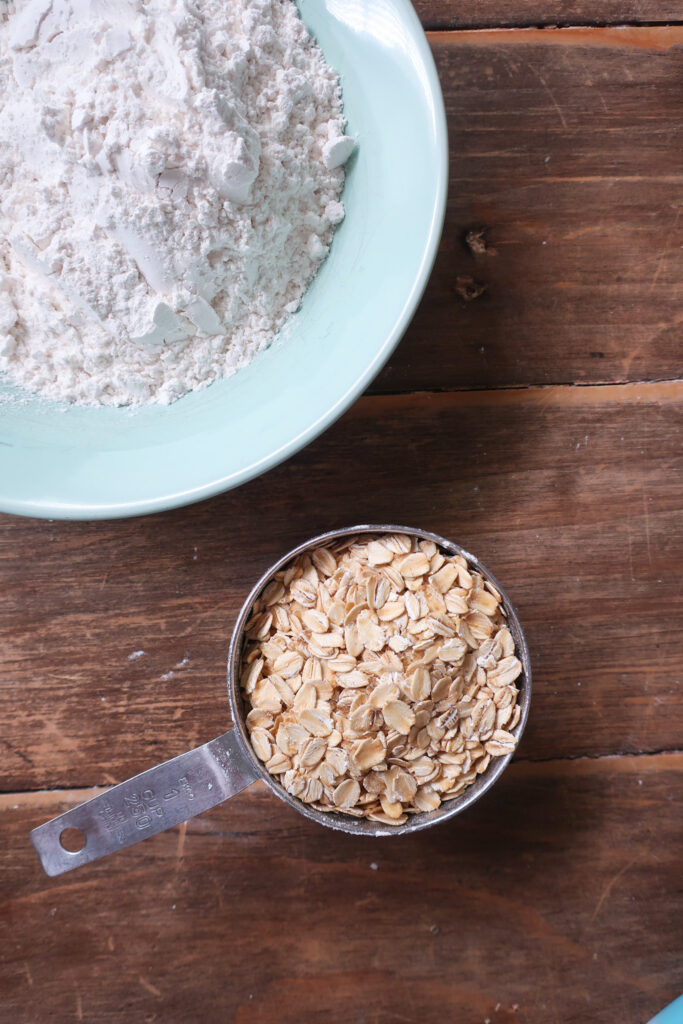 ingredients for dark chocolate oat cookies in a bowl; brown sugar, granulated sugar, and butter in a bowl; dark chocolate oat sea salt cookies; dark chocolate coconut cookies; dark chocolate chip cookies with sprinkles; measuring cup filling with traditional oats