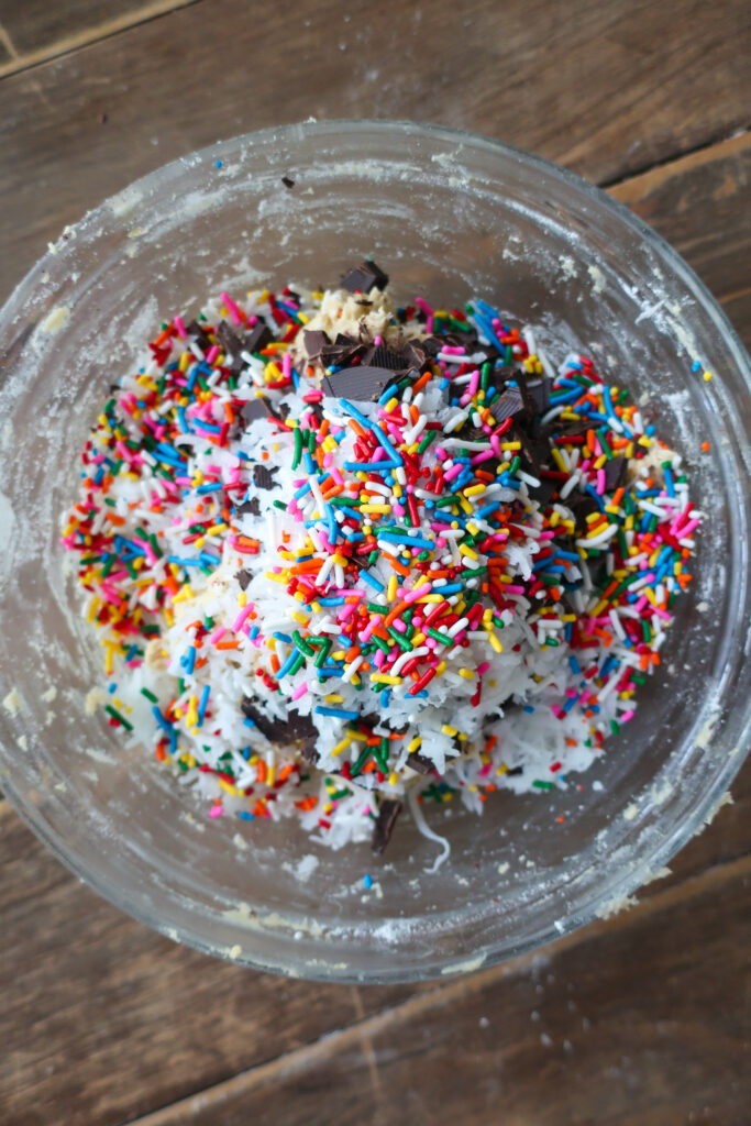 sprinkle packed cookie dough; ingredients for dark chocolate oat cookies in a bowl; brown sugar, granulated sugar, and butter in a bowl; dark chocolate oat sea salt cookies; dark chocolate coconut cookies; dark chocolate chip cookies with sprinkles; measuring cup filling with traditional oats