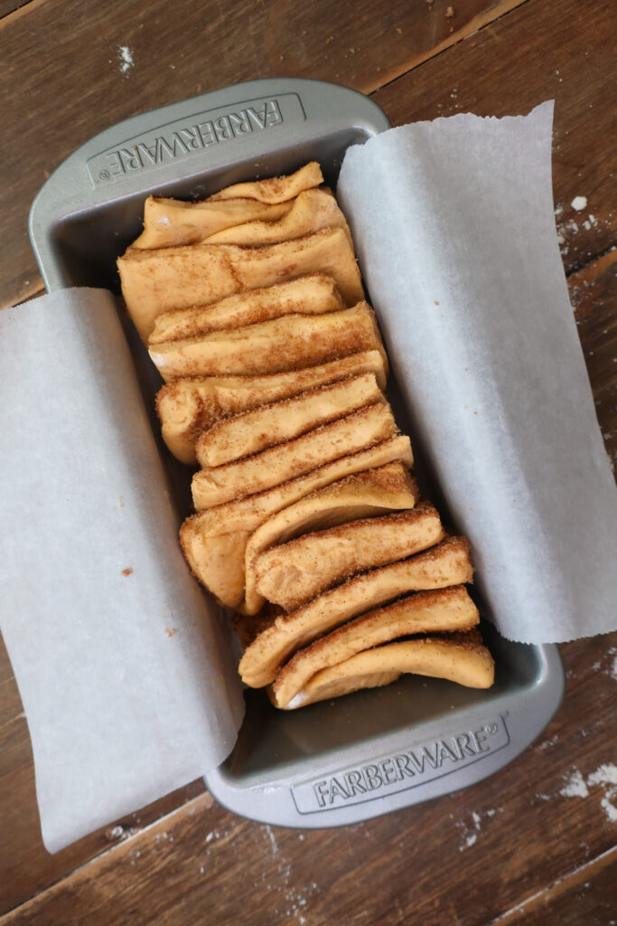 cinnamon sugar coated dough stacked in loaf pan ahead of rise for cinnamon sugar sweet potato pull-apart bread