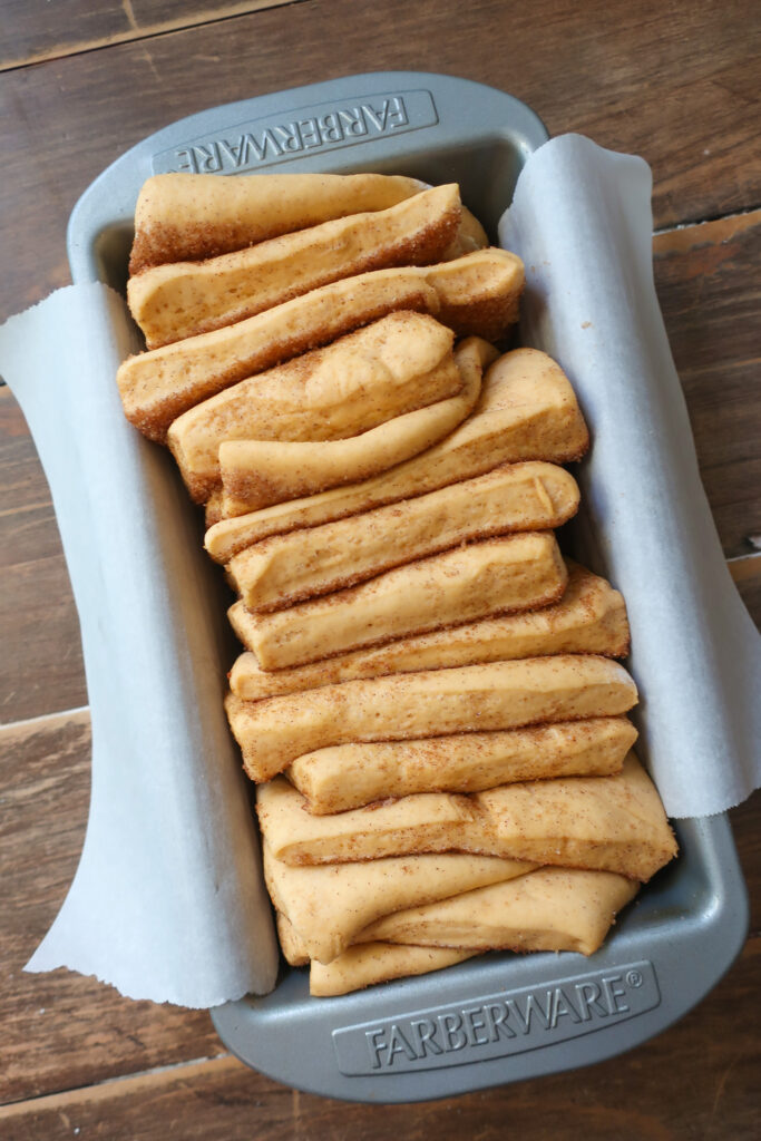 cinnamon sugar coated dough stacked in loaf pan after rise for cinnamon sugar sweet potato pull-apart bread