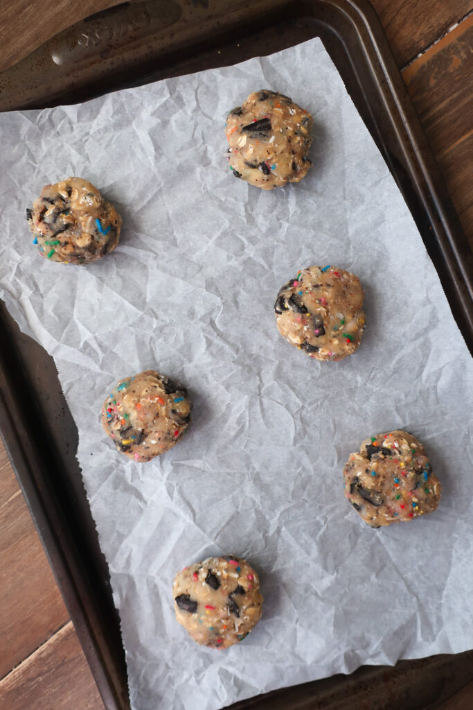 sprinkle cookie dough; dark chocolate oat sea salt cookies; dark chocolate coconut cookies; dark chocolate chip cookies with sprinkles; measuring cup filling with traditional oats