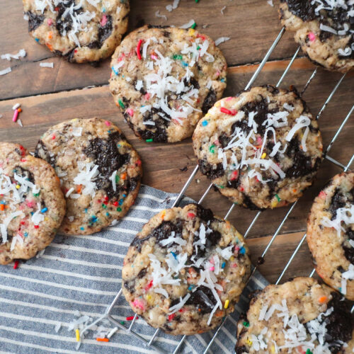 baked cookies on baking tray in sunshine; dark chocolate oat sea salt cookies; dark chocolate coconut cookies; dark chocolate chip cookies with sprinkles; measuring cup filling with traditional oats