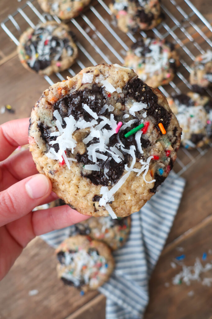 baked cookies on baking tray in sunshine; dark chocolate oat sea salt cookies; dark chocolate coconut cookies; dark chocolate chip cookies with sprinkles; measuring cup filling with traditional oats