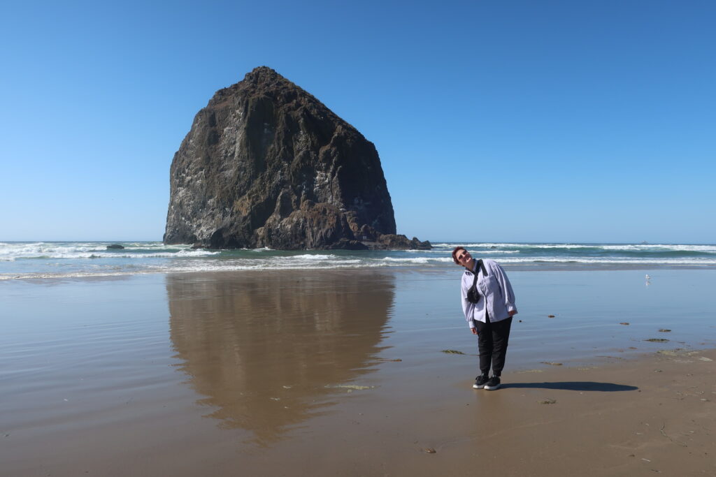 woman on cannon beach near haystack rock in oregon, usa; cannon beach oregon; haystack rock oregon; solo travel female; solo travel tips; tips for women who travel