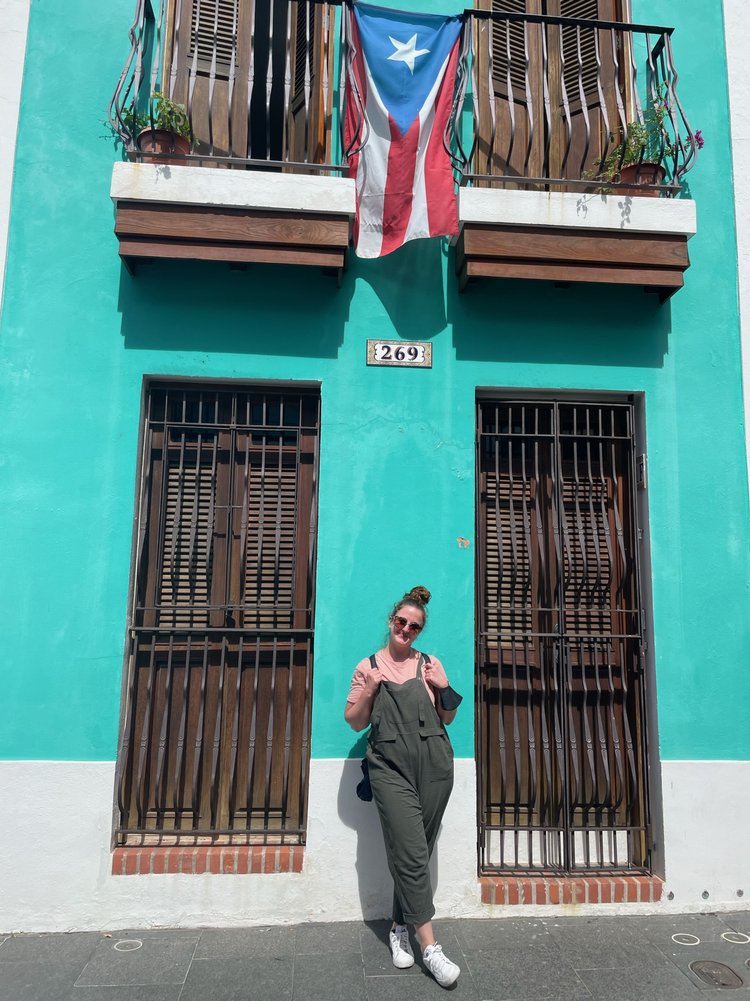 woman standing under puerto rican flag; puerto rico, usa, north america; friend trip; puerto rico in february; puerto rico itinerary; san juan puerto rico; women who travel; female travel; long week trip inspiration