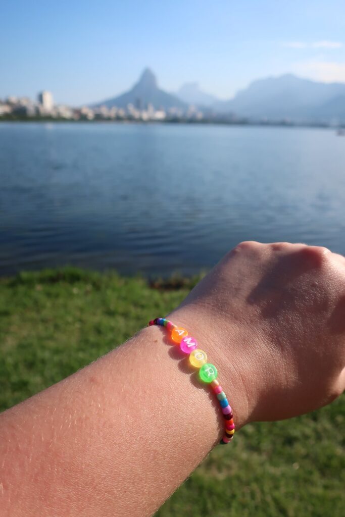 woman showing beaded bracelet near water in Rio de Janeiro, Brazil; backpacking south america; solo backpacking trip; female backpacking trip tips; solo travel tips; solo female travel; brazil travel itinerary