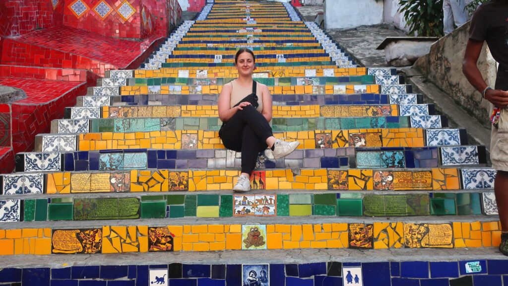 woman sitting on colorful Selarón Staircase in Rio de Janeiro, Brazil; backpacking south america; solo backpacking trip; female backpacking trip tips; solo travel tips; solo female travel; brazil travel itinerary