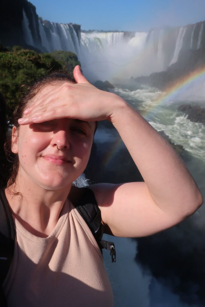 woman on balcony looking at iguazu falls in argentina and brazil; backpacking south america; solo backpacking trip; female backpacking trip tips; solo travel tips; solo female travel; argentina travel itinerary