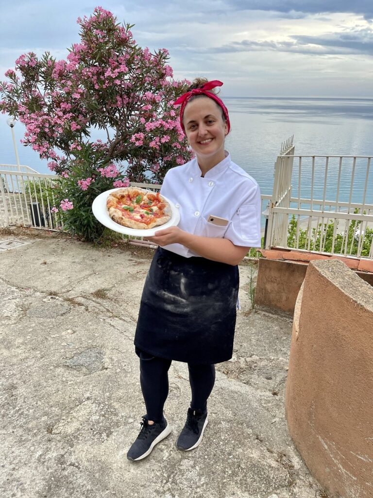 woman posing with made from scratch pizza in italian cooking course in calabria, italy; italian cooking class; solo travel; solo female travel; international culinary school; what to do before you go to culinary school; home chef