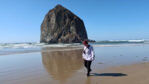 woman smiling near haystack rock on cannon beach in oregon, usa, north america; solo travel; solo female travel; roadtrip usa; friend trip; west coast beach; oregon in october