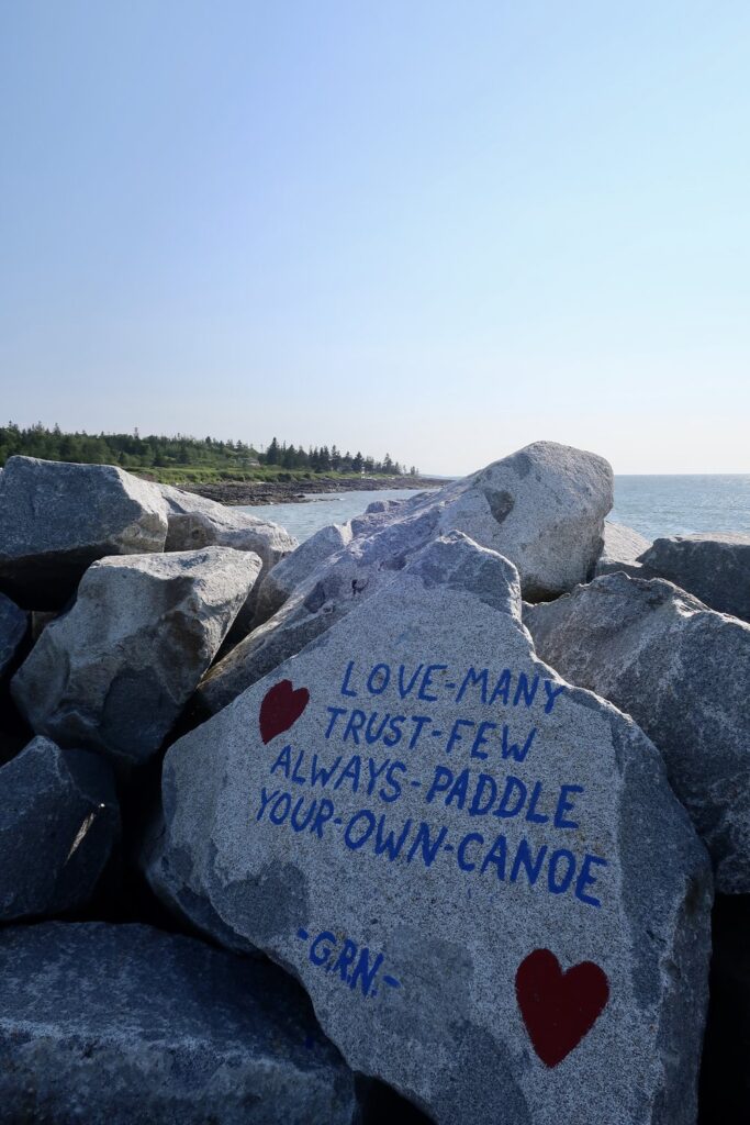 love many trust few always paddle your own canoe written on boulder near bay of fundy in nova scotia, canada; motivational quotes; motivational sign; positive sign; positive affirmation