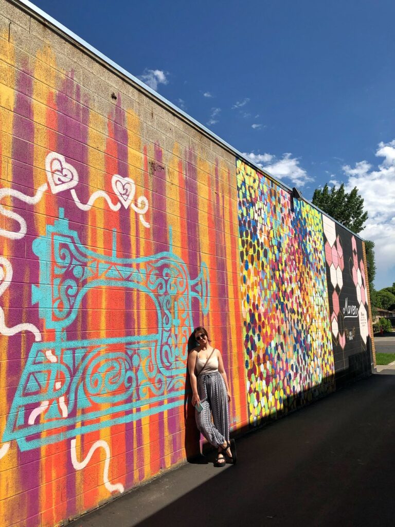 woman leaning against sewing machine mural in salt lake city, utah, usa; mother daughter trip; road trip south west; south west usa; utah travel itinerary; road trip tips; female travel; united states national park trip