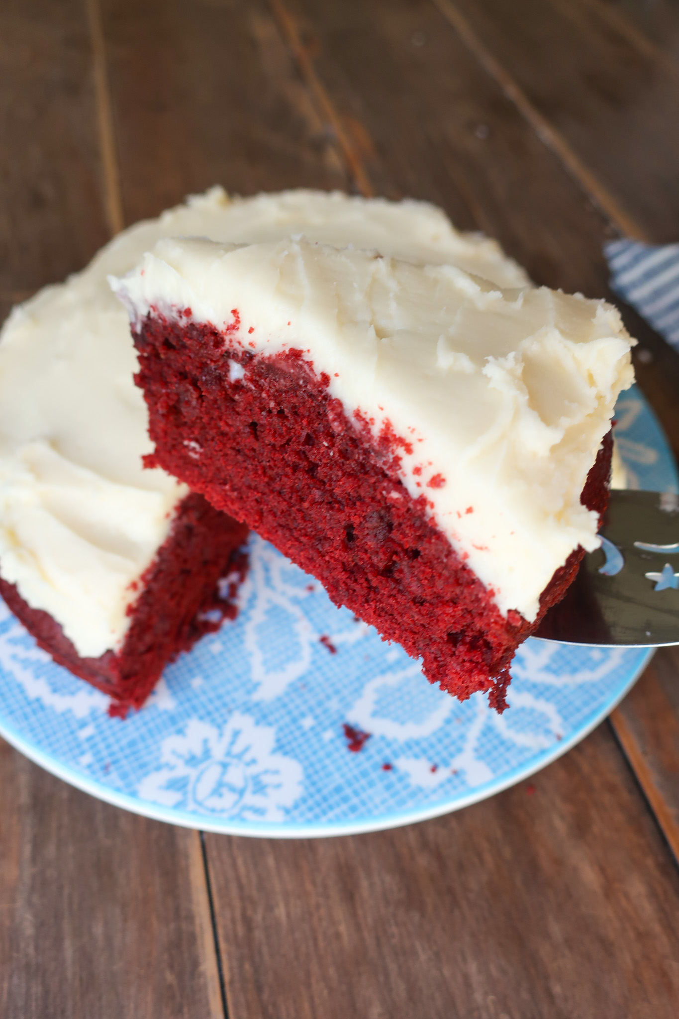 red velvet cake with cream cheese frosting on blue floral plate