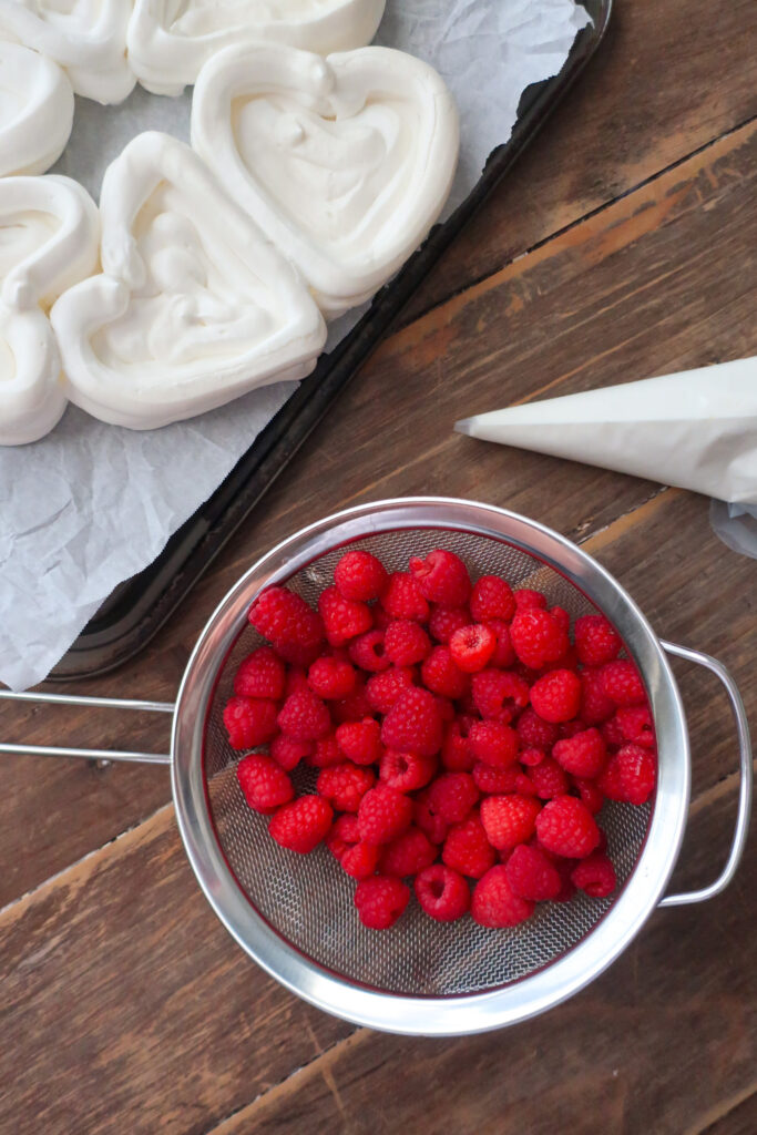 baked french meringue piped into hearts for pavlova hearts wreath with french meringue, piped into heart baskets and filled with fresh whipped cream and fresh raspberries