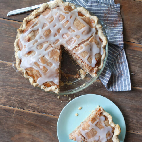 easy cinnamon roll pie with cream cheese filling, baked cinnamon pie on striped blue and white napkin on wooden table, slice of easy cinnamon roll pie with cream cheese filling