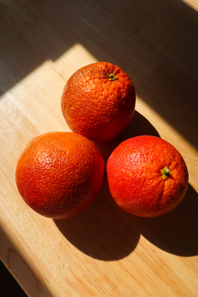 blood oranges in sunlight on wooden table, fresh blood oranges for blood orange galette drizzled with homemade salted caramel