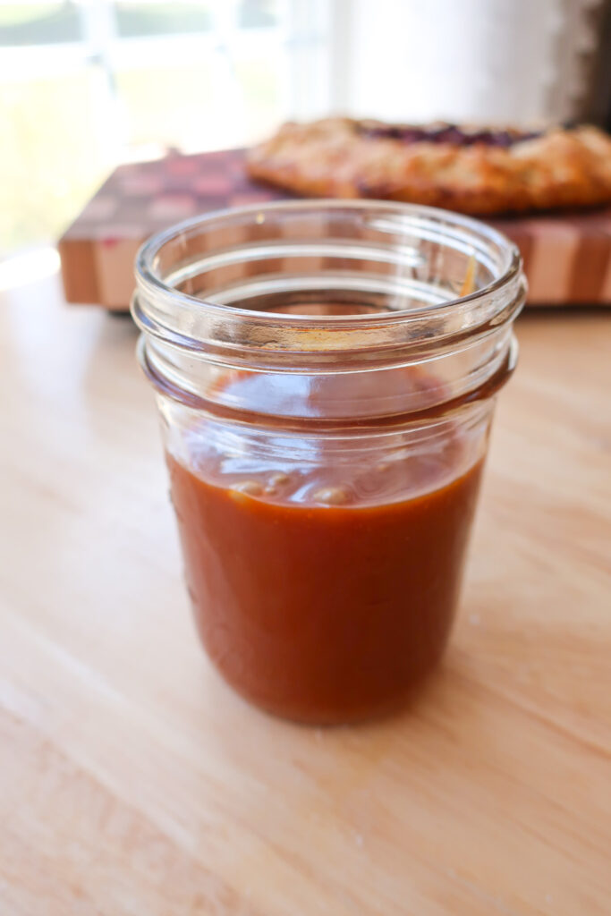 mason jar filled with homemade 10 minute salted caramel sitting on light wood countertop