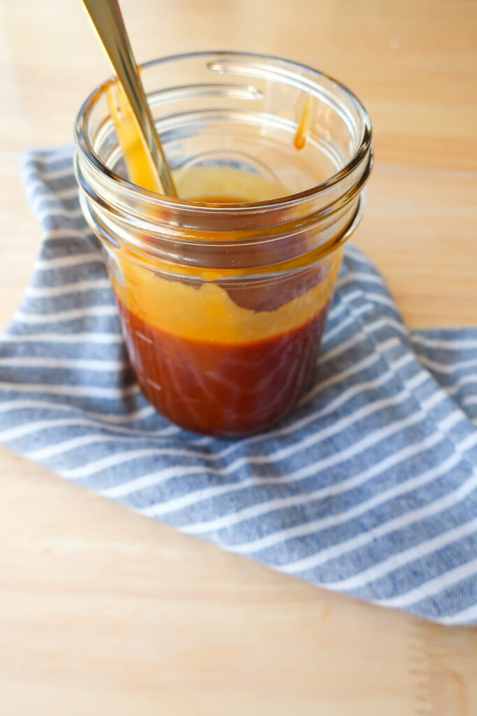 mason jar filled with homemade 10 minute salted caramel sitting on striped blue and white napkin