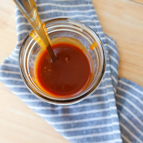 mason jar filled with homemade 10 minute salted caramel sitting on striped blue and white napkin