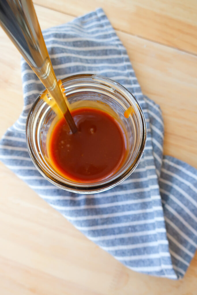 mason jar filled with homemade 10 minute salted caramel sitting on striped blue and white napkin