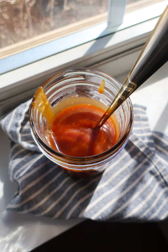 mason jar filled with homemade 10 minute salted caramel sitting in the sun on striped blue and white napkin