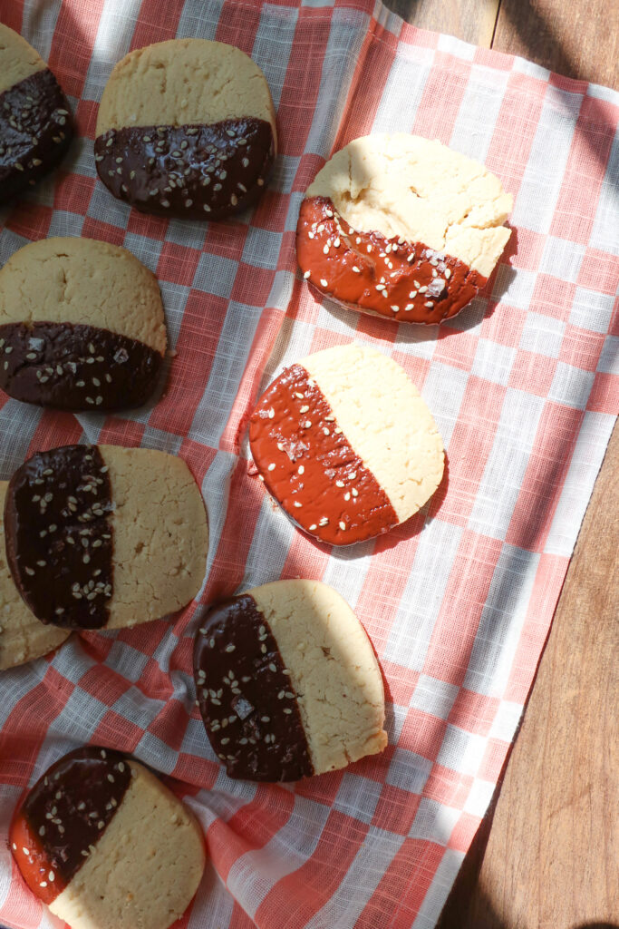 shortbread cookies dipped in chocolate, chocolate dipped cookies on pink and white cloth, easy bittersweet chocolate dipped sesame shortbread cookies