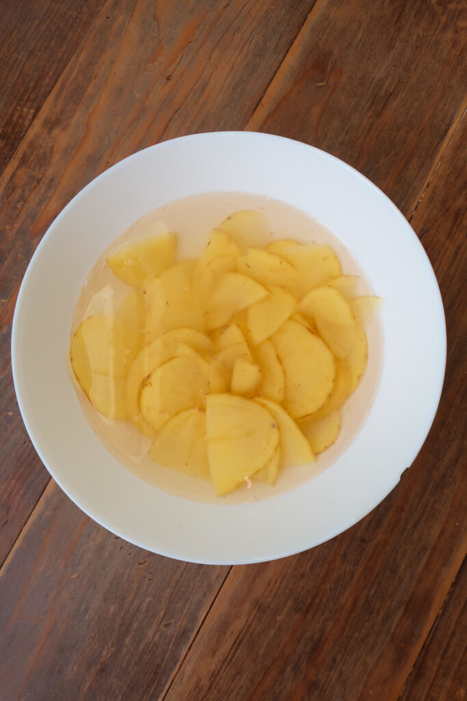 sliced potatoes in bowl of water