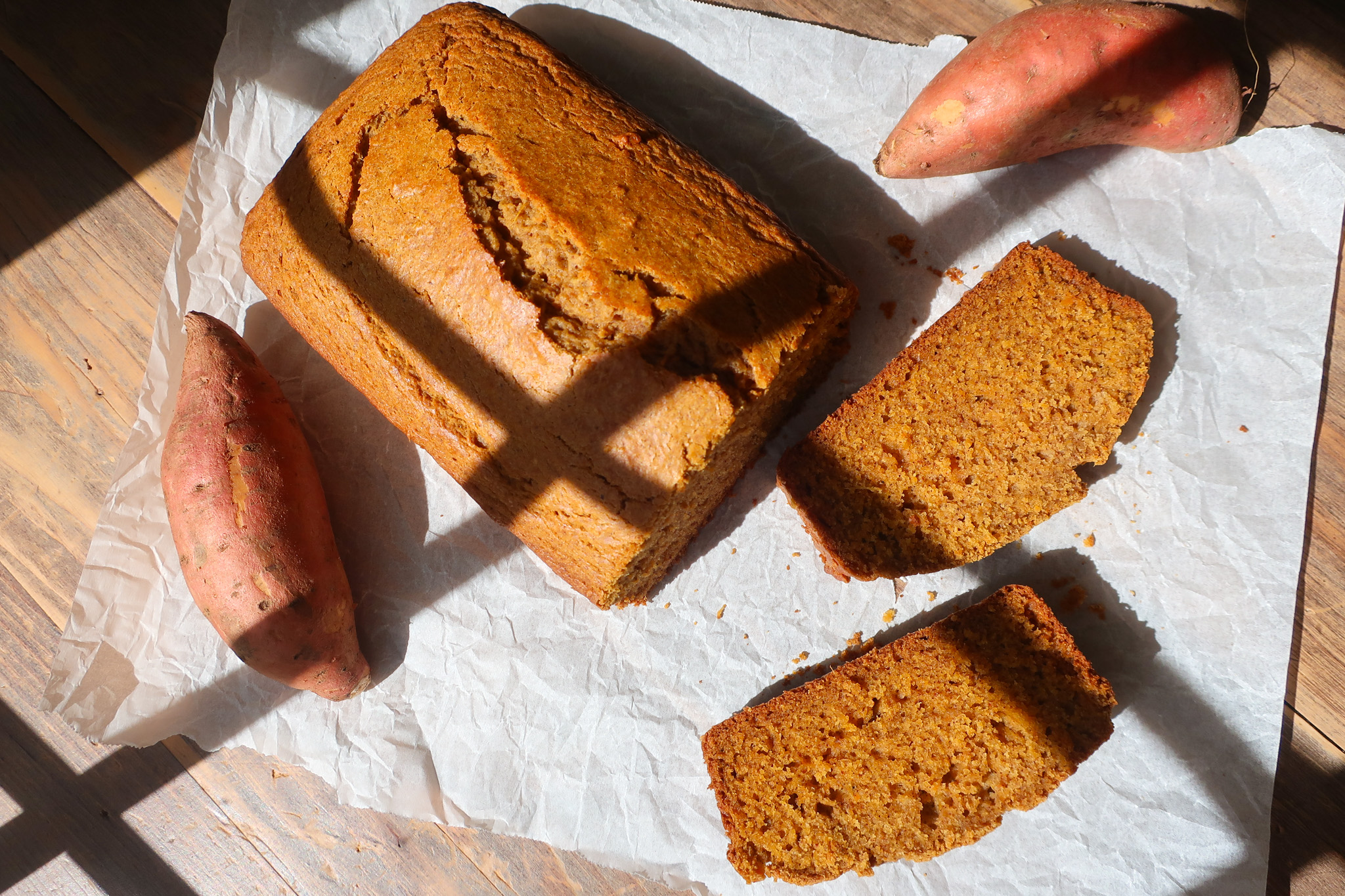 sliced sweet potato bread on parchment paper with sweet potatoes