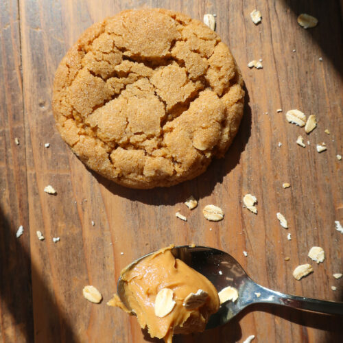 peanut butter cookie next to spoon of peanut butter