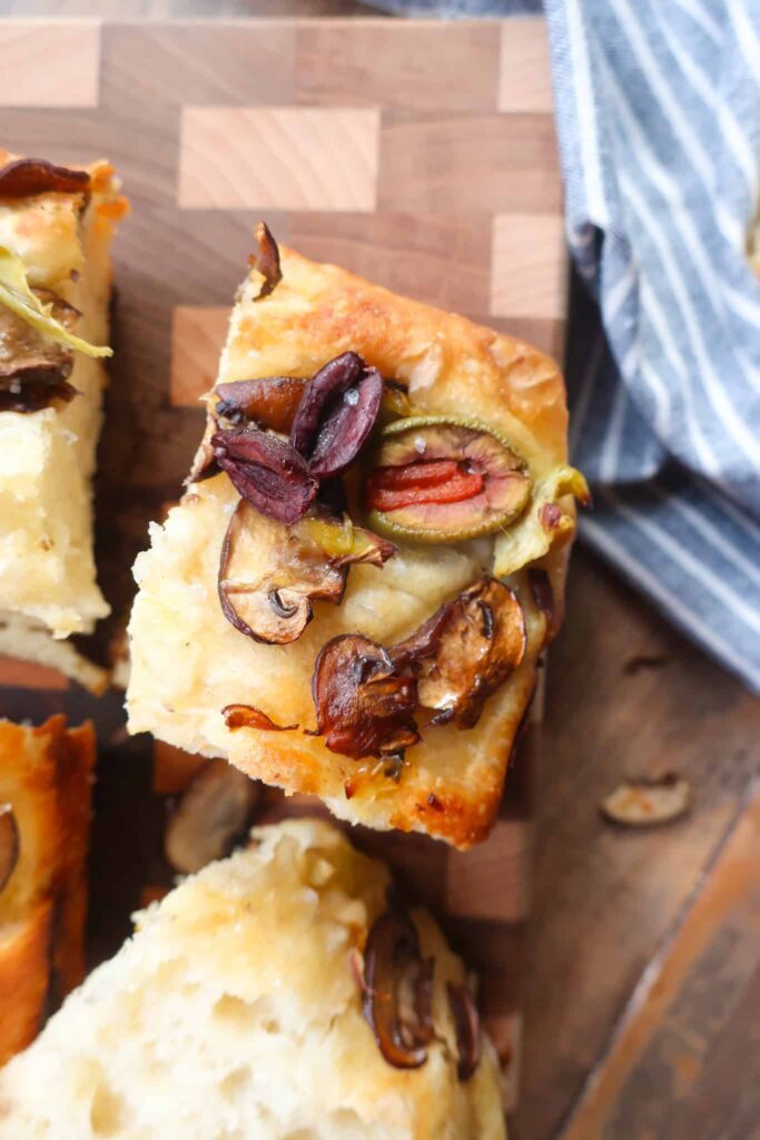 piece of focaccia topped with olives artichokes and mushrooms