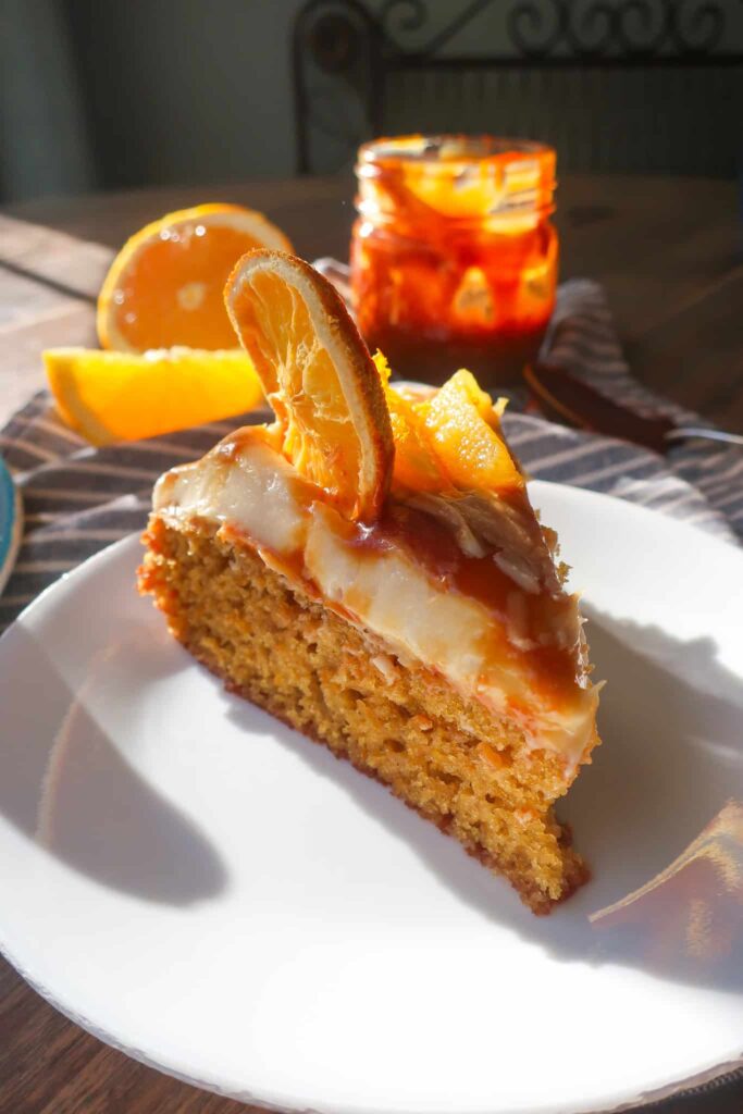 slice of olive oil cake with salted caramel cream cheese frosting on white plate
