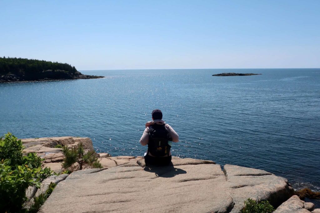 woman sitting on rock in acadia national park maine