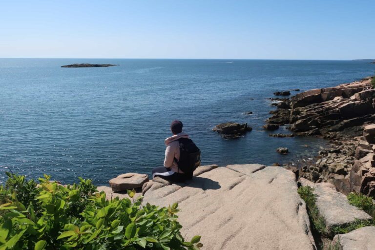 woman sitting on rock in acadia national park maine