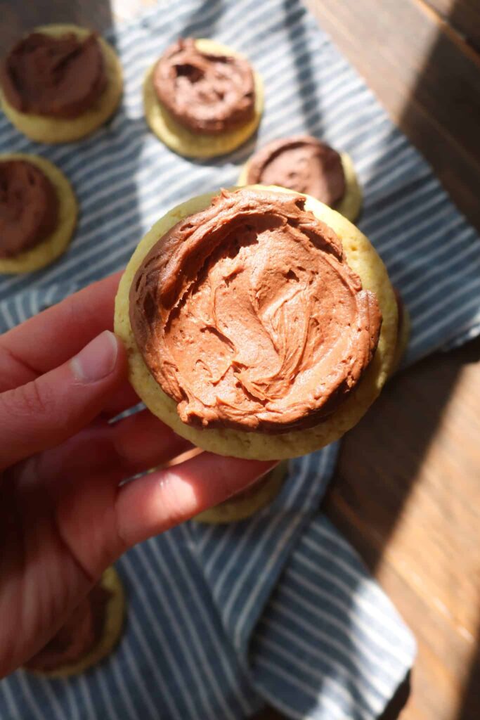 holding yellow cake cookie with chocolate buttercream