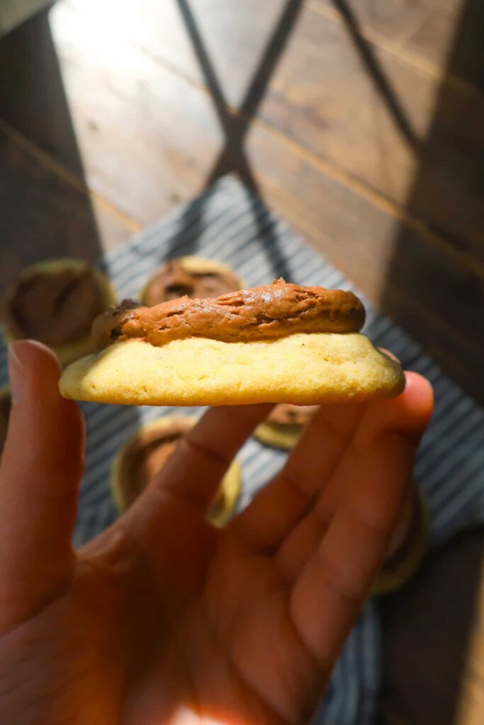 holding side of yellow cake cookies with chocolate buttercream