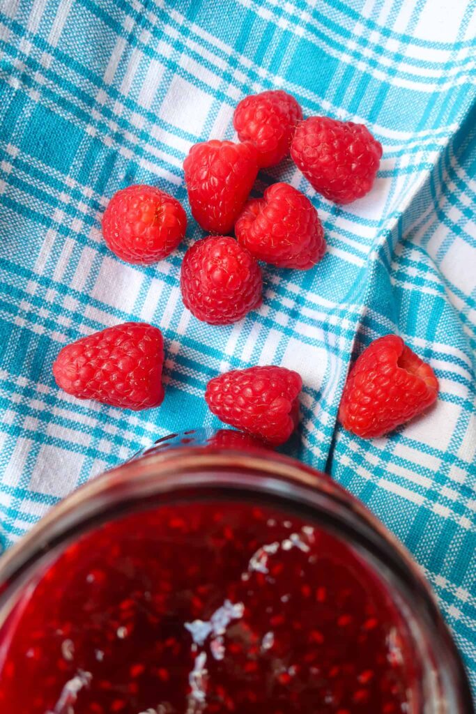 fresh raspberries next to jar of jam