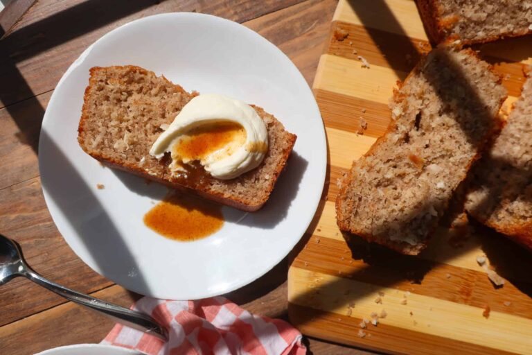 slice of coconut spice loaf cake topped with whipped cream and dessert sauce